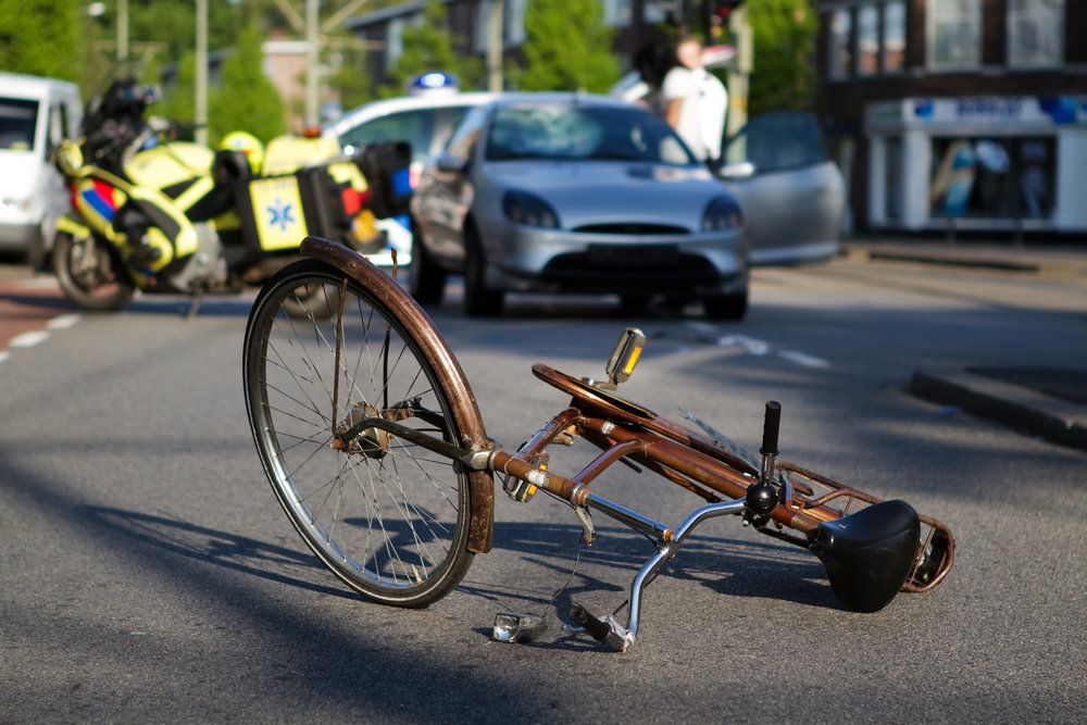 Bike lying on its side in the street with a car in background